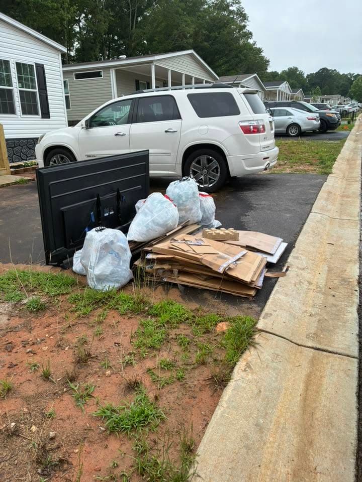 A driveway with a pile of bags, boxes and a TV, before