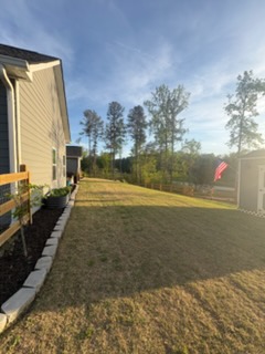 A freshly edged mulch bed running along the side of a house, lawn beyond