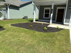 A fresh mulch bed with new plantings along the front of a home, laid by Mason Worx