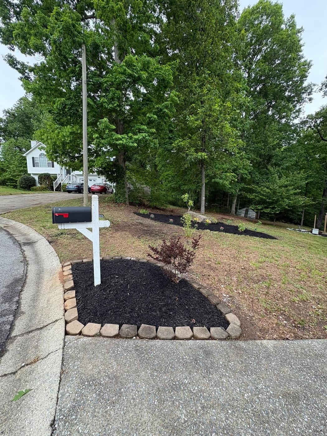 A mailbox bed finished in black mulch with a stone border