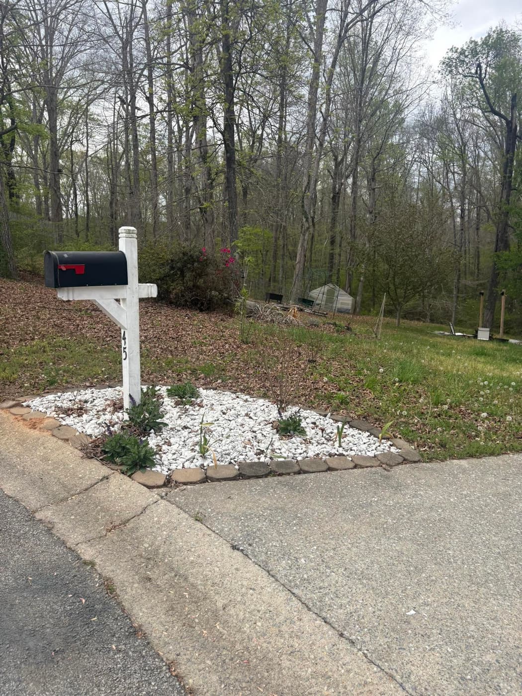 A mailbox bed finished in white stone with new plantings