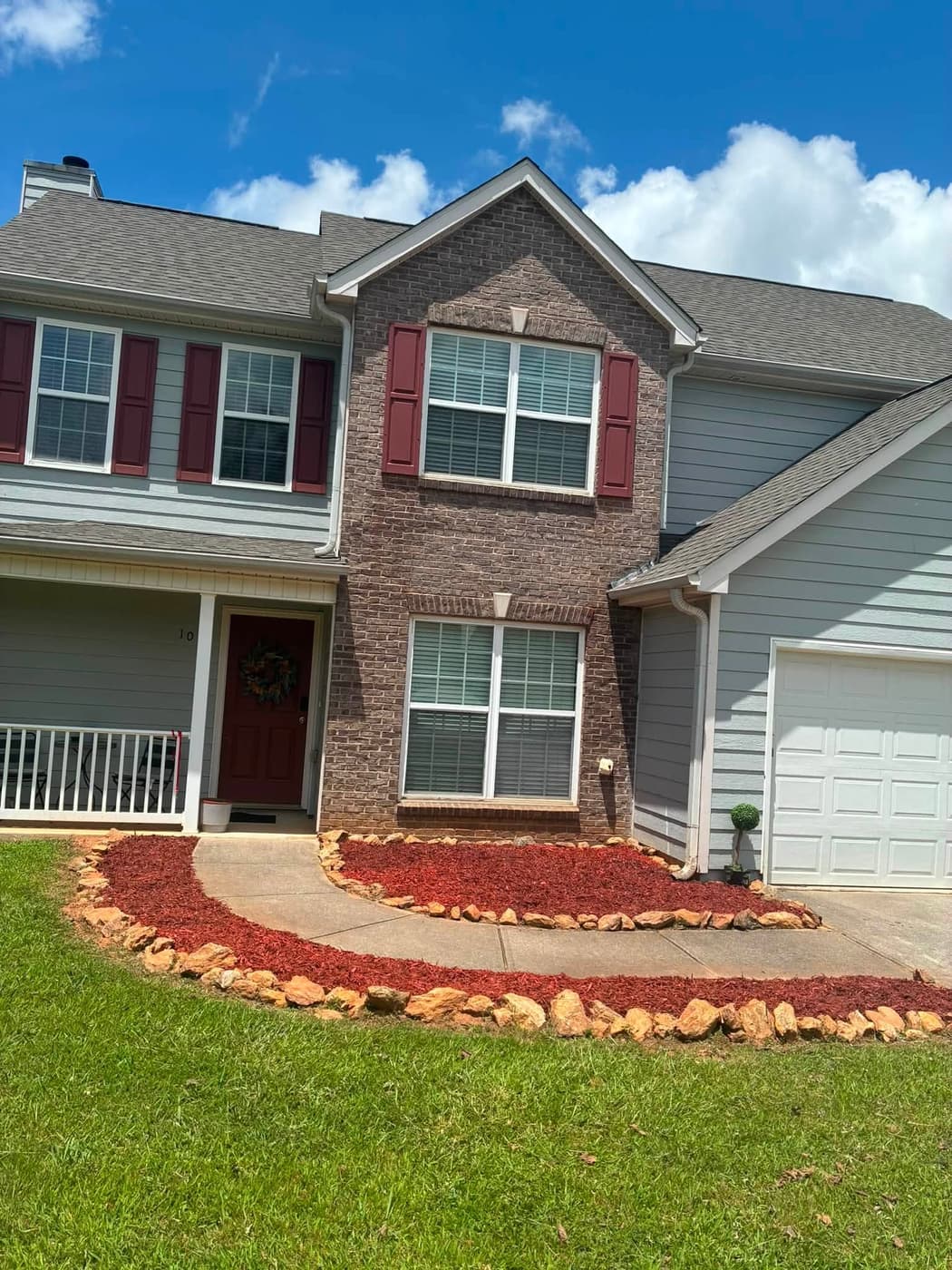 Red mulch and river-stone edging along a curved driveway