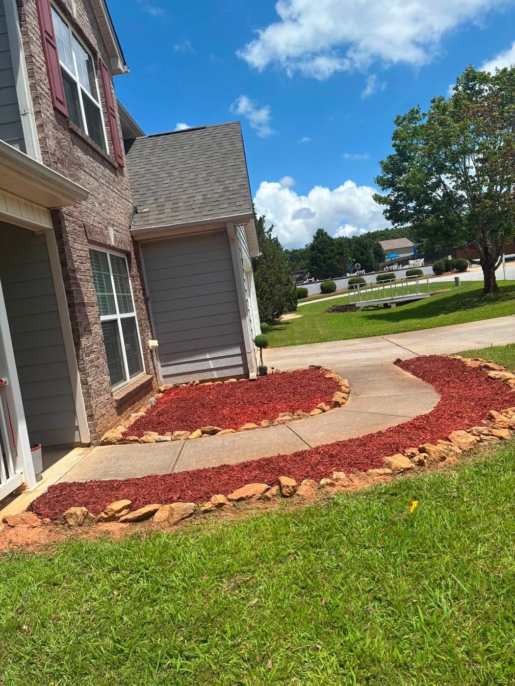 Red mulch and stone edging following the curve of a driveway