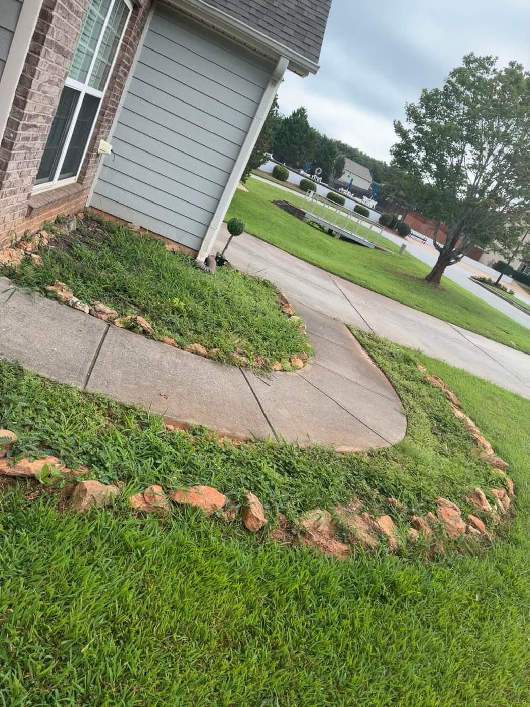 A clean driveway edged with stone-bordered mulch beds