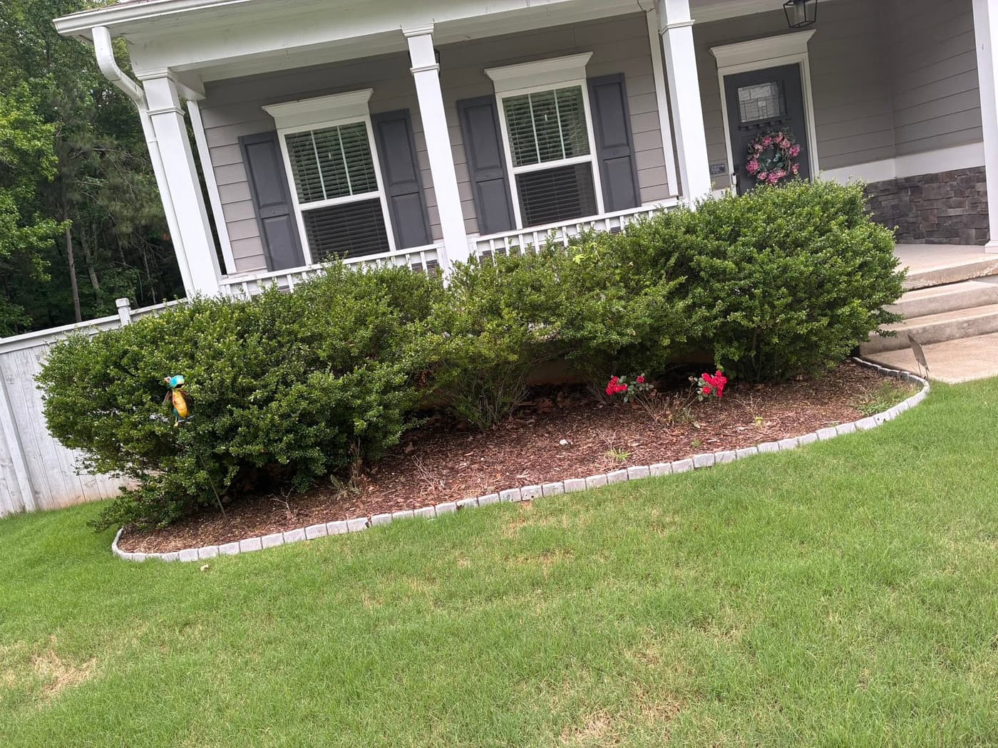 Fresh mulch beds with stone edging along a front porch