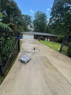 A surface cleaner running down a concrete driveway during a Mason Worx pressure wash